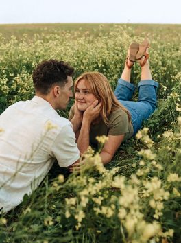 Couple lying together among yellow canola flowers