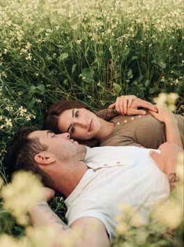 Couple lying in the grass among canola flowers
